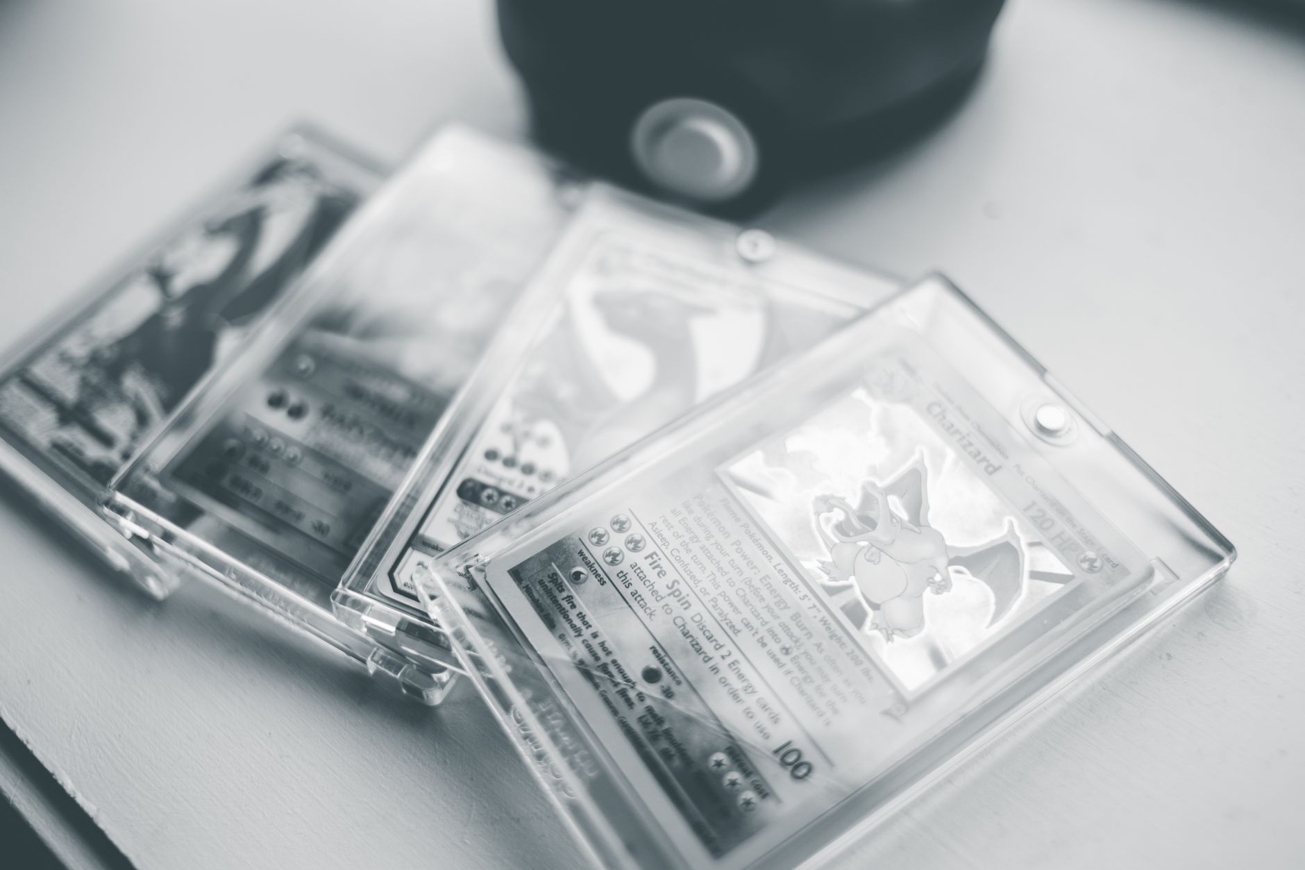 cartes Pokémon rangées dans des étuis rigides transparents, reflets visibles sur le plastique